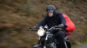 Photo of Tom on his motorcycle with a large red sack, delivering customer orders.