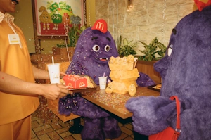 Picture of Grimace celebrating his birthday at a McDonalds from the W+K campaign for Grimace's Birthday.